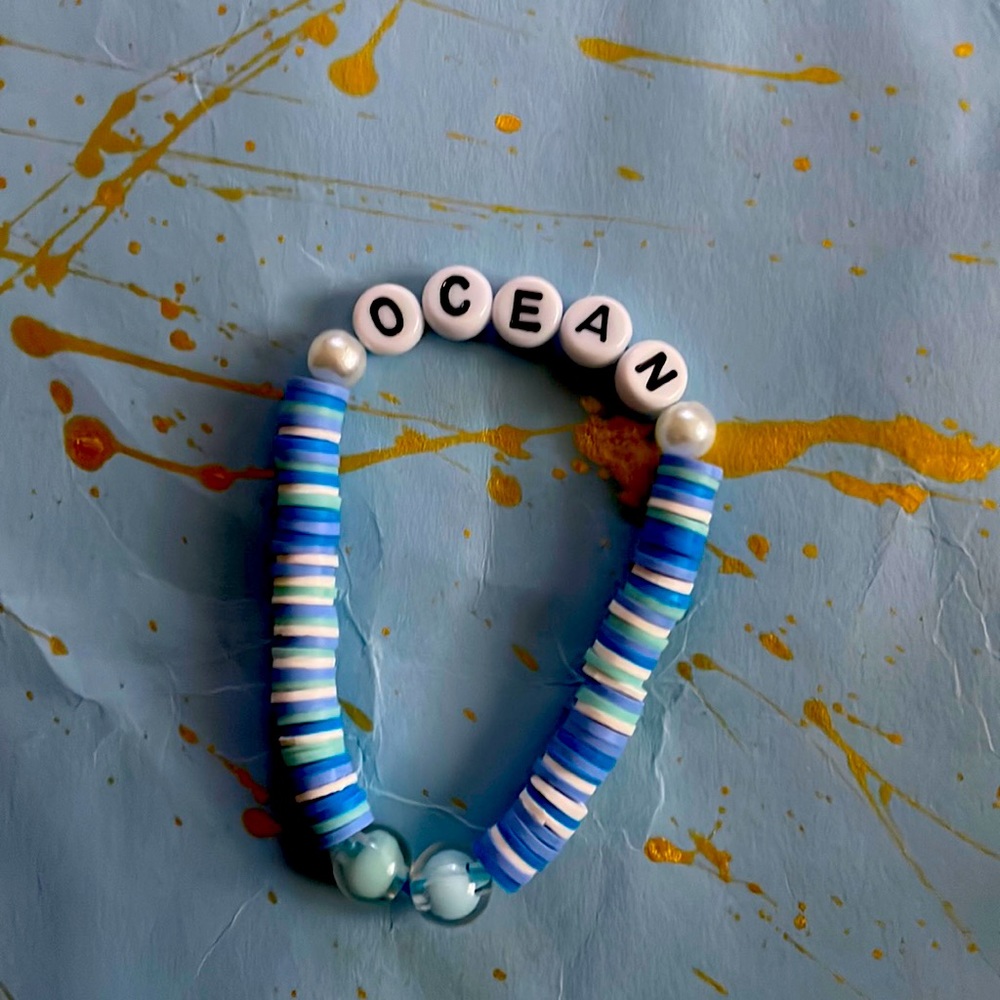 It has blue string and blue beads, and it says ocean with two pearl beads